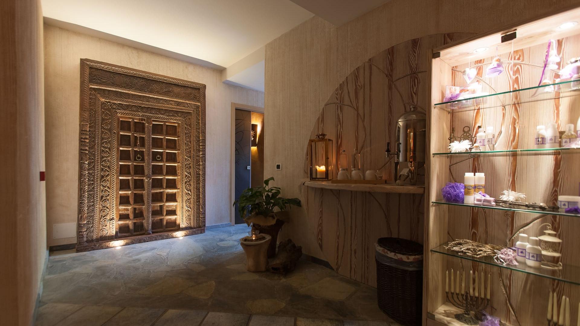 Ambiente rilassante con porta decorata, candele, e prodotti benessere esposti in una vetrina.
