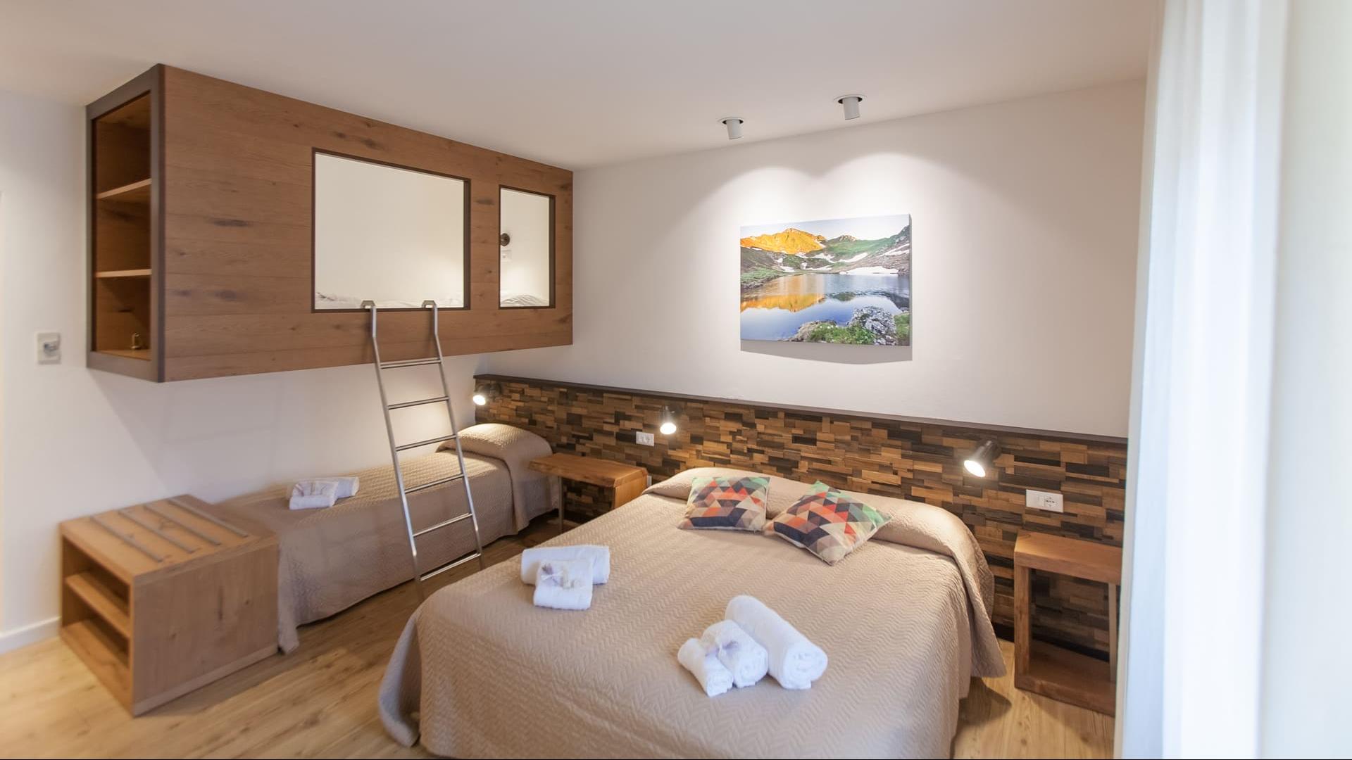 Camera accogliente con letto matrimoniale, letto a castello, e decorazioni in legno naturale.