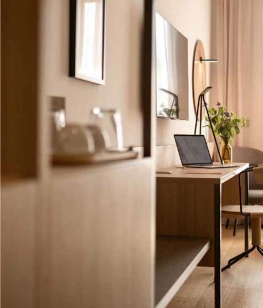 Studio accogliente con luce calda, laptop, fiori freschi e arredi moderni in legno.