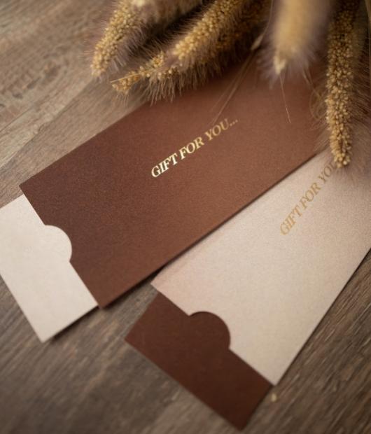 Eleganti buste regalo marroni su legno, con scritta dorata 'Gift for you'.