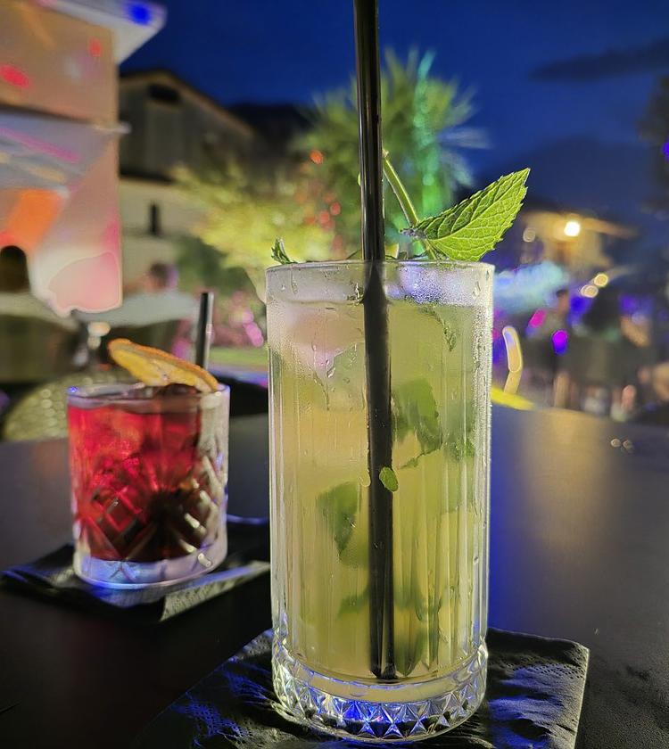 Cocktail colorati su tavolo notturno, atmosfera vivace e luminosa, serata estiva all'aperto.