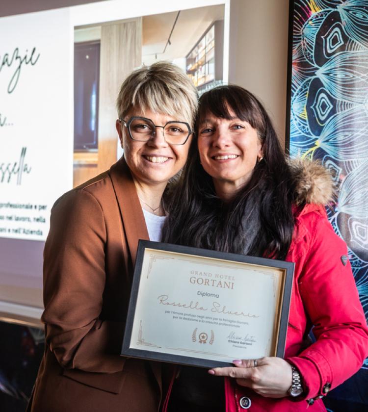 Due donne sorridenti con un diploma, atmosfera di gratitudine e celebrazione.