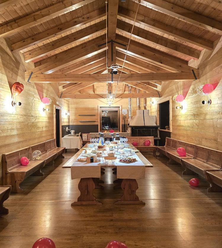 Sala rustica decorata per festa, tavola imbandita, palloncini rossi creano atmosfera accogliente.