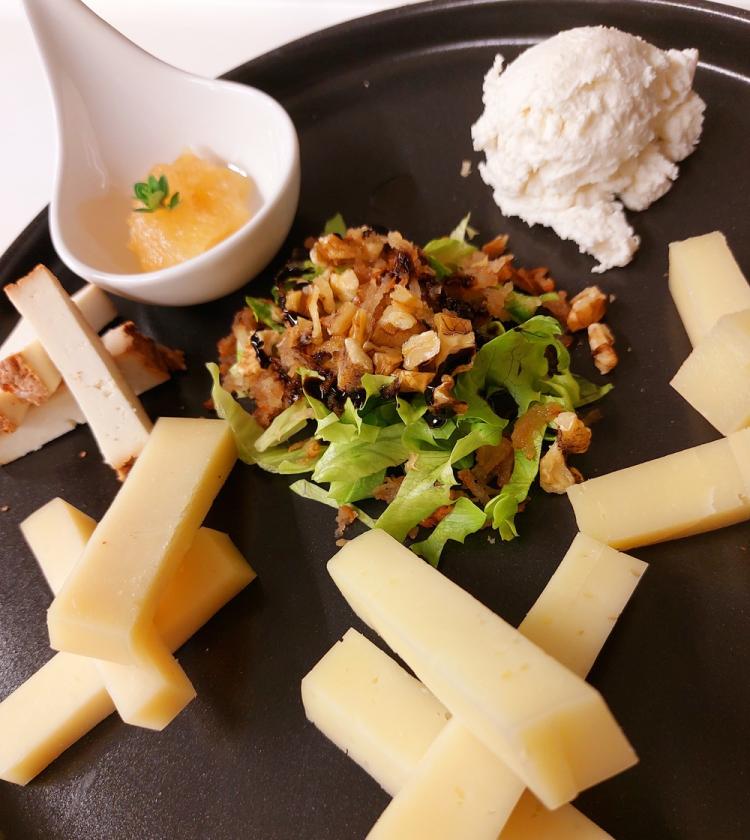 Piatto elegante con formaggi, insalata e salse, evocando raffinatezza e delizia sensoriale.