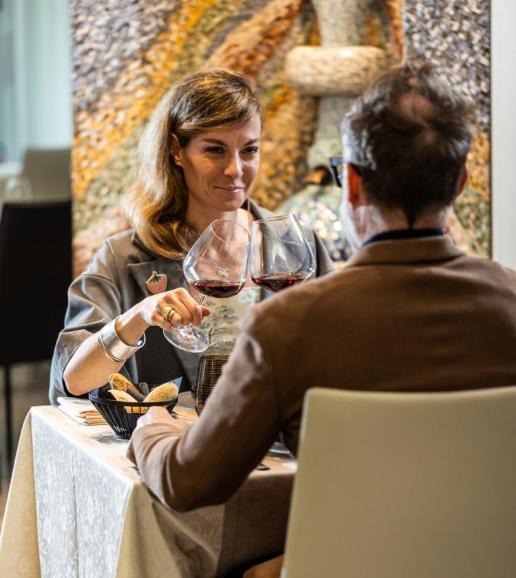 Una coppia brinda con vino rosso, atmosfera intima e calda in un ristorante elegante.